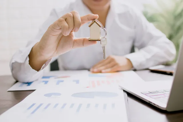 Real estate professional presenting a house model with keys, symbolizing property investment and ownership. How to Improve Real Estate Lead Generation by Diagnosing the Real Constraint