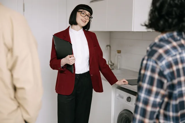 Real estate agent with clients in a modern kitchen during apartment viewing. Professional and engaging. Tax deductions for realtor marketing, explained with IRS rules